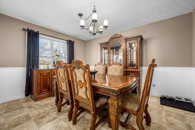 dining space featuring a chandelier, wainscoting, and a textured ceiling