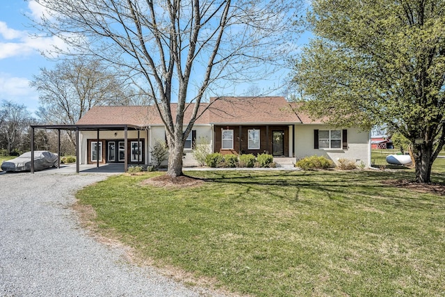 view of front of house featuring gravel driveway, a front yard, and a carport