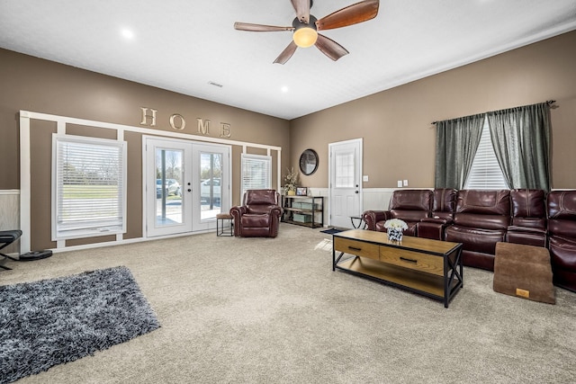living room featuring carpet, ceiling fan, french doors, and a wainscoted wall