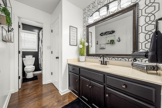 bathroom featuring wood finished floors, vanity, toilet, and baseboards