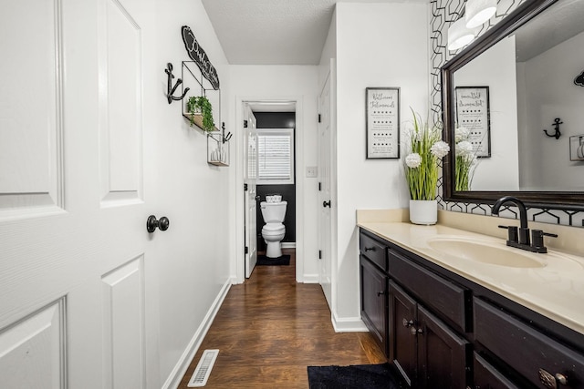 bathroom featuring wood finished floors, toilet, vanity, and baseboards