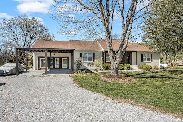 ranch-style home featuring brick siding, roof with shingles, a front yard, driveway, and french doors