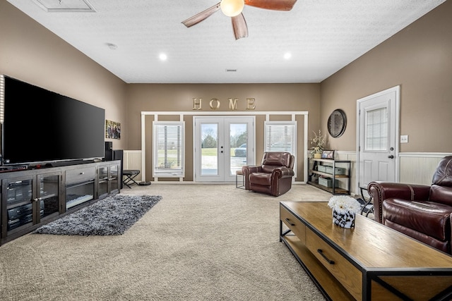 living room featuring carpet, wainscoting, ceiling fan, french doors, and a textured ceiling