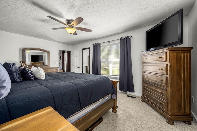 bedroom with light carpet, a textured ceiling, ceiling fan, and baseboards
