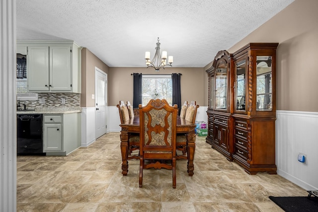 dining room with a chandelier, wainscoting, and a textured ceiling