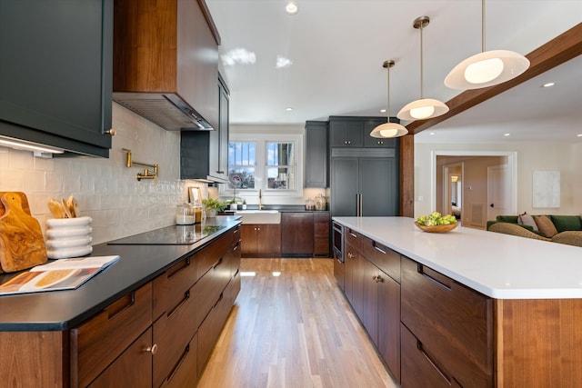 1908 Beechwood Ave, Nashville, TN 37212 - kitchen featuring black electric cooktop, a large island, backsplash, light wood finished floors, and custom range hood