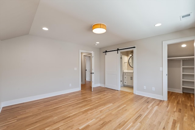 1908 Beechwood Ave, Nashville, TN 37212 - unfurnished bedroom featuring a barn door, a walk in closet, light wood finished floors, recessed lighting, and baseboards