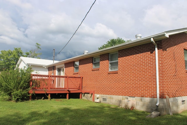 rear view of house with a lawn, brick siding, and a deck