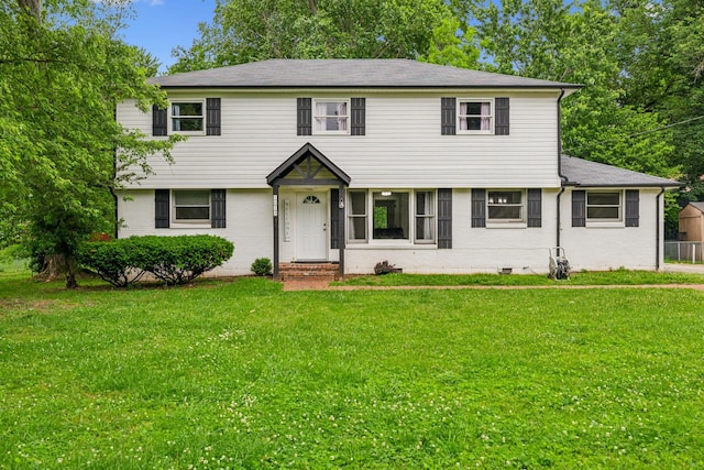 colonial home featuring a front lawn, brick siding, and a shingled roof