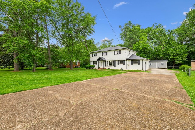 view of front of home featuring concrete driveway, a front lawn, a shingled roof, and view of scattered trees