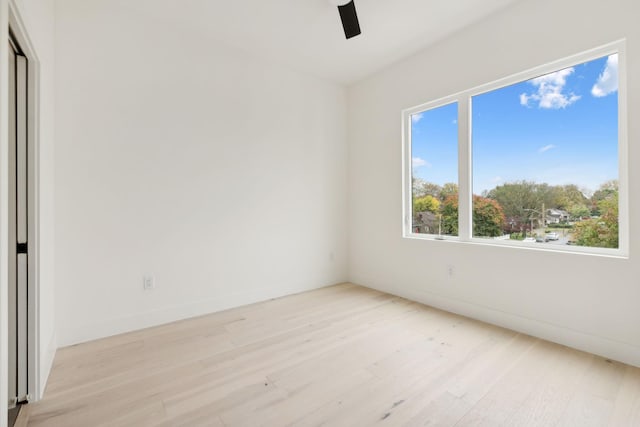 empty room with wood finished floors, a ceiling fan, and baseboards