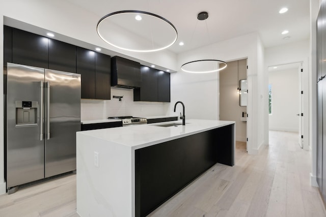 kitchen featuring stainless steel appliances, range hood, dark cabinetry, light wood-type flooring, and recessed lighting