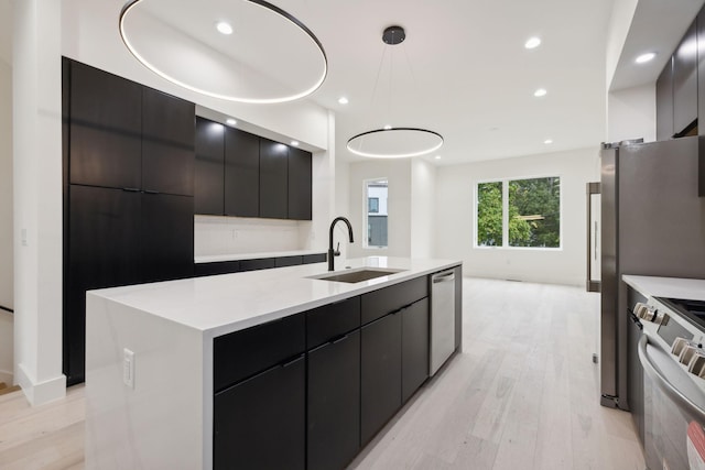 kitchen with a sink, modern cabinets, light wood-style floors, stainless steel appliances, and recessed lighting