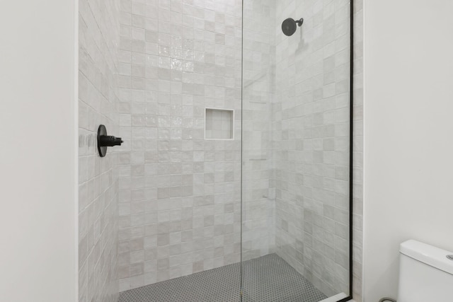 bathroom with a tile shower and toilet