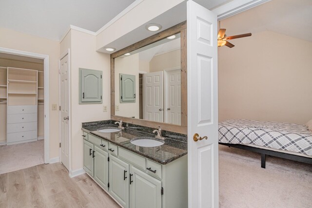 full bath with double vanity, wood finished floors, lofted ceiling, ceiling fan, and baseboards