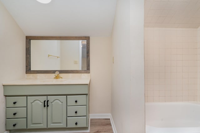 bathroom with vanity, baseboards, wood finished floors, and bathtub / shower combination