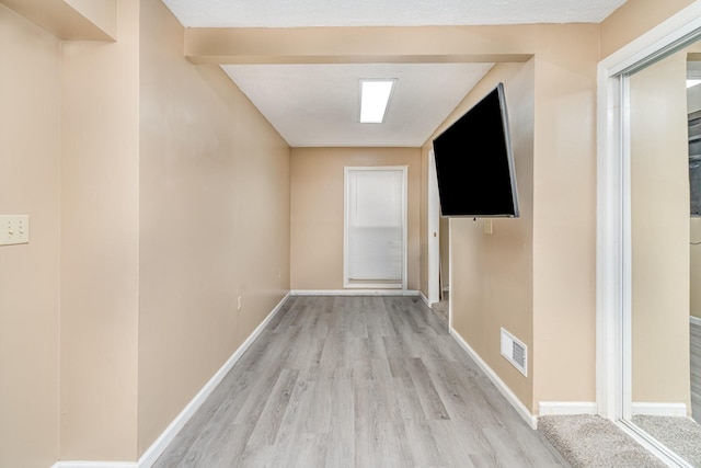 corridor with light wood-type flooring and baseboards