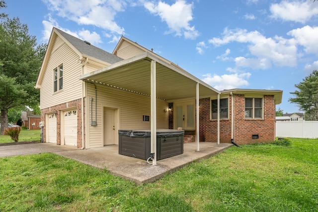 back of house featuring a hot tub, brick siding, asphalt driveway, an attached garage, and french doors
