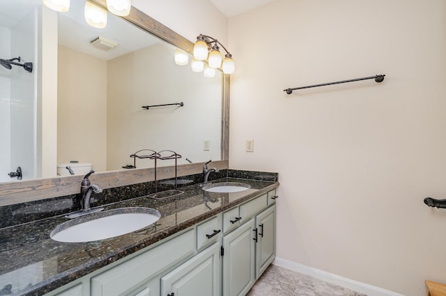 bathroom featuring toilet, double vanity, and baseboards