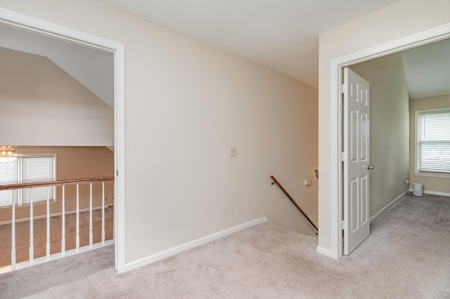 corridor with an upstairs landing, carpet, and baseboards