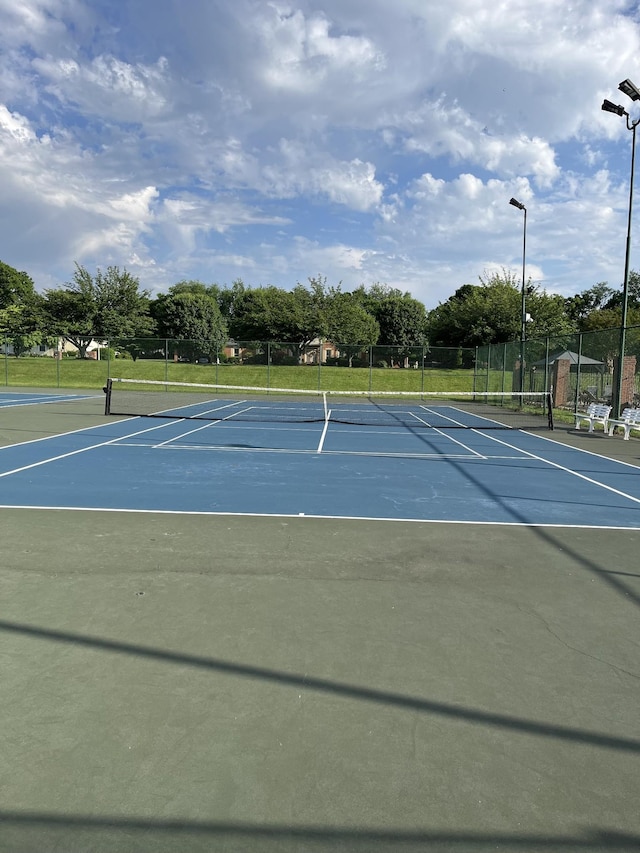 view of tennis court featuring community basketball court and fence