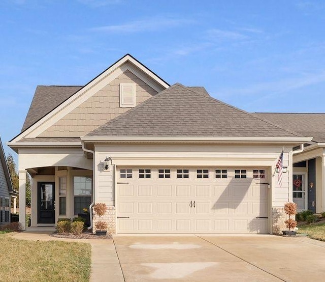 view of front facade featuring an attached garage, driveway, and roof with shingles