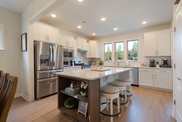 kitchen with appliances with stainless steel finishes, open shelves, light wood-type flooring, decorative backsplash, and recessed lighting