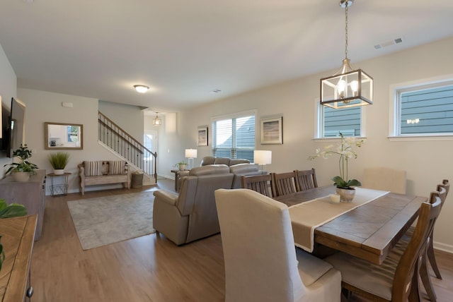dining space featuring wood finished floors, stairway, a chandelier, and baseboards