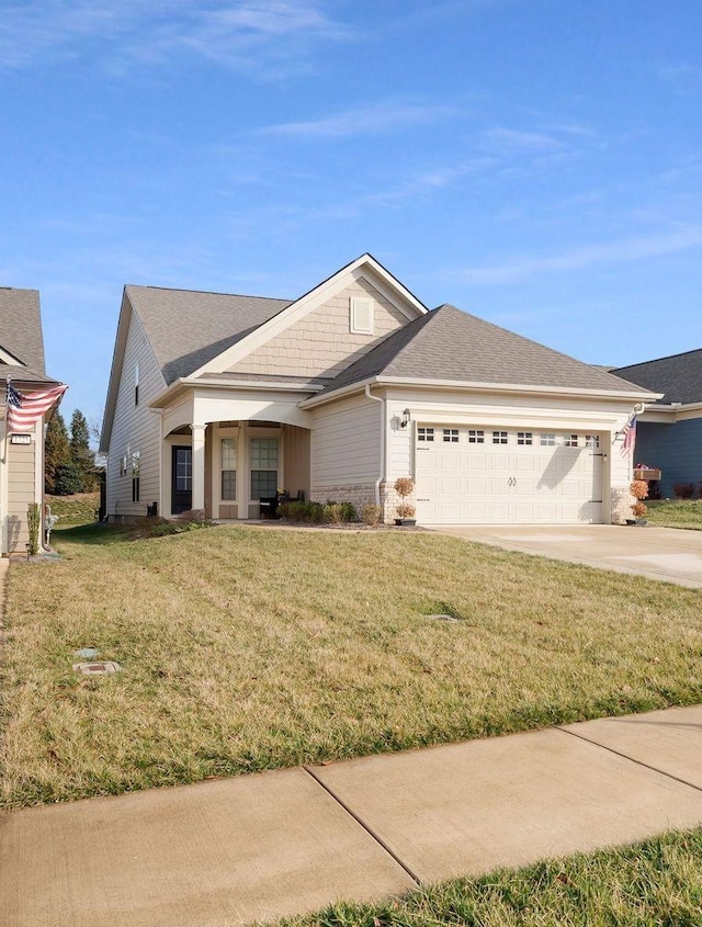 view of front facade featuring an attached garage, driveway, a front yard, and roof with shingles