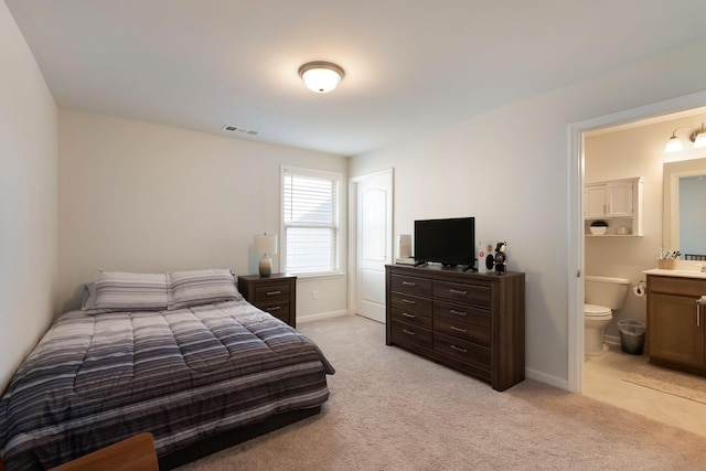 bedroom with light carpet, baseboards, and ensuite bathroom