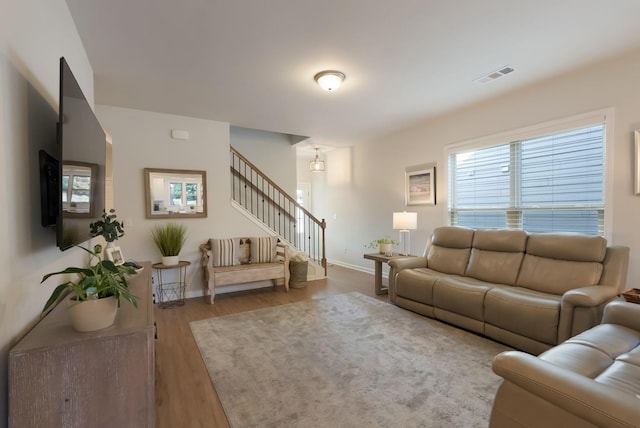 living room with stairs, wood finished floors, and baseboards