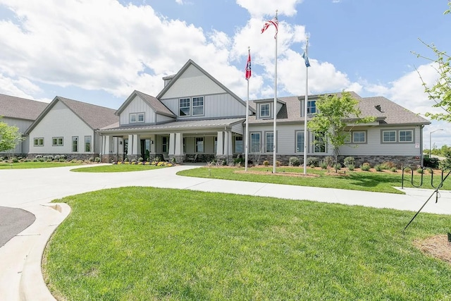 view of front facade with a front lawn, covered porch, stone siding, and curved driveway