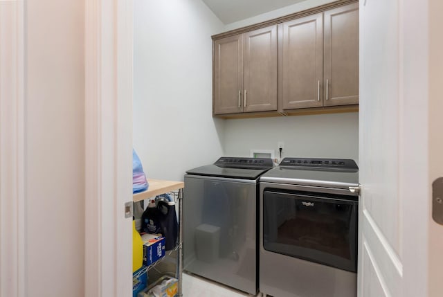 clothes washing area featuring separate washer and dryer and cabinet space
