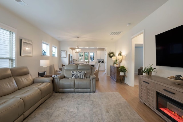 living area featuring light wood finished floors and a glass covered fireplace