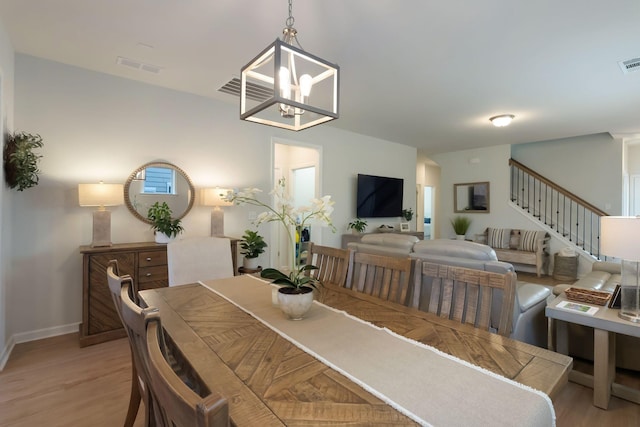 dining room with light wood-type flooring, baseboards, a chandelier, and stairway