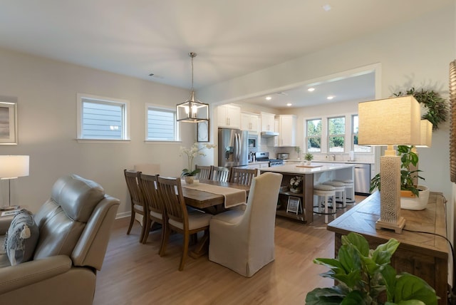 dining area with light wood-type flooring, recessed lighting, and a chandelier
