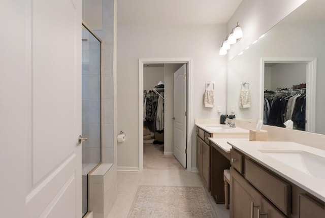 bathroom featuring a tile shower, vanity, tile patterned flooring, and a spacious closet