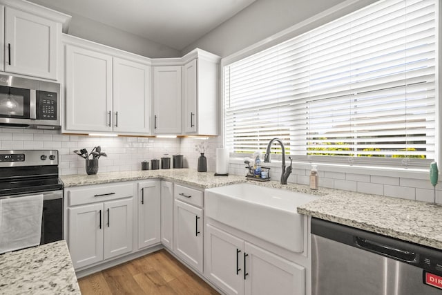 1112 Malinda Ln, Greenbrier, TN 37073 - kitchen featuring appliances with stainless steel finishes, a sink, light wood-style flooring, white cabinetry, and decorative backsplash