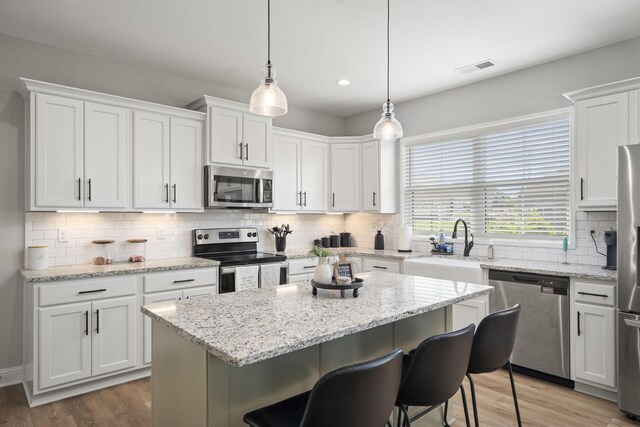 1112 Malinda Ln, Greenbrier, TN 37073 - kitchen with appliances with stainless steel finishes, a sink, white cabinets, backsplash, and light wood-style flooring