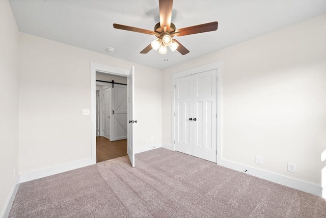 1936 Flats Rd, Cunningham, TN 37052 - unfurnished bedroom with carpet flooring, baseboards, a closet, ceiling fan, and a barn door