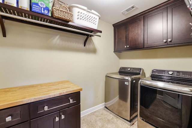 washroom featuring washer and clothes dryer, cabinet space, and baseboards