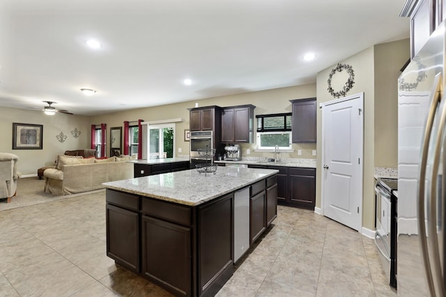 kitchen with a kitchen island with sink, electric range, open floor plan, a sink, and dark brown cabinetry