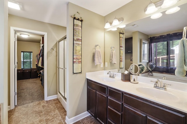 full bathroom featuring a stall shower, double vanity, and baseboards