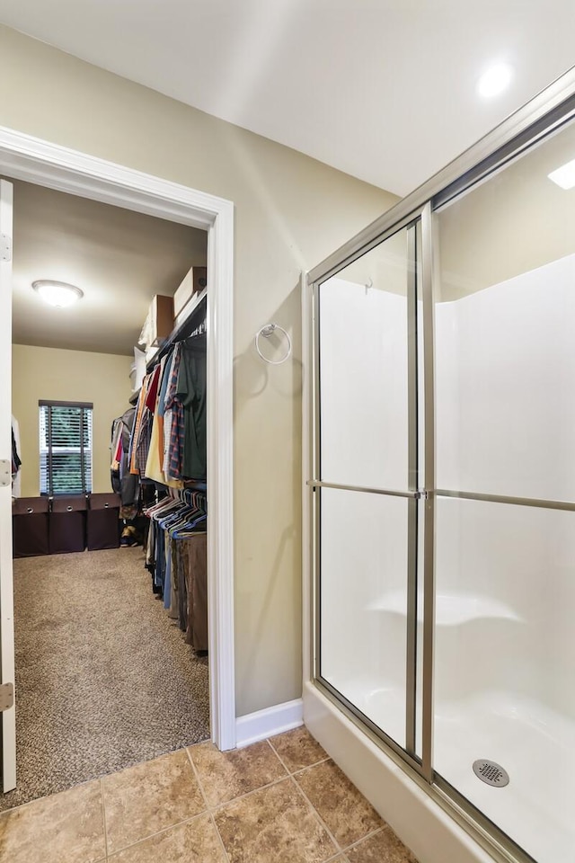 bathroom featuring a shower stall, a spacious closet, and tile patterned floors