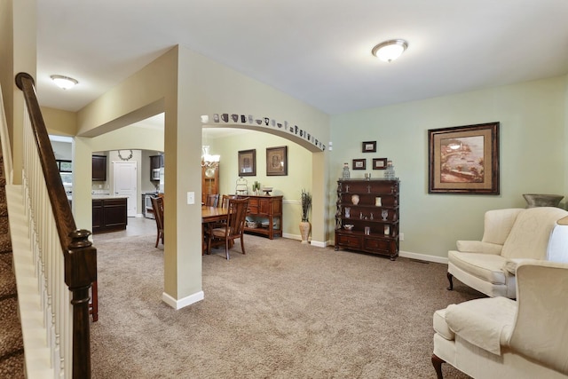 living area featuring arched walkways, carpet, stairs, and baseboards