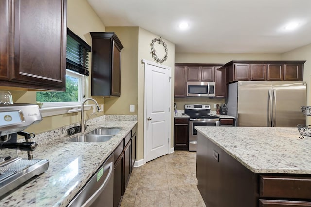 kitchen with appliances with stainless steel finishes, a sink, dark brown cabinetry, and recessed lighting