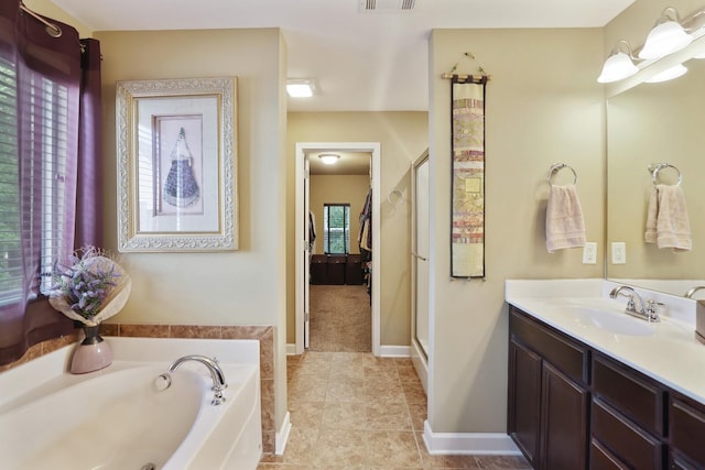 bathroom with a garden tub, a shower stall, vanity, tile patterned flooring, and baseboards