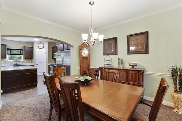 dining area with arched walkways, crown molding, a chandelier, and light carpet