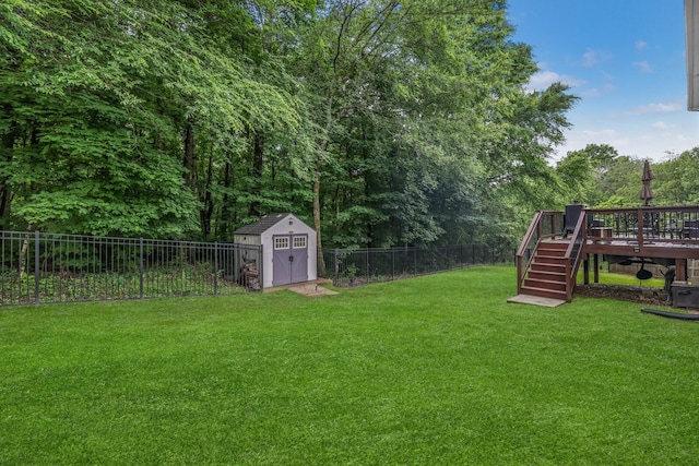 view of yard featuring a deck, stairway, a storage shed, and an outbuilding