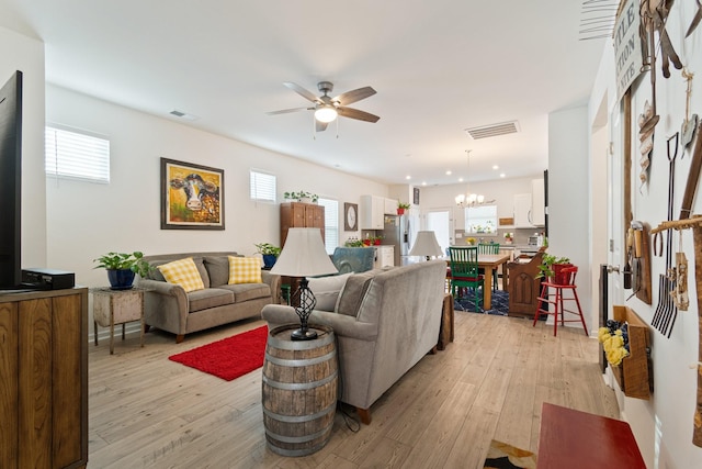 living room with light wood-style flooring, ceiling fan, a chandelier, and recessed lighting